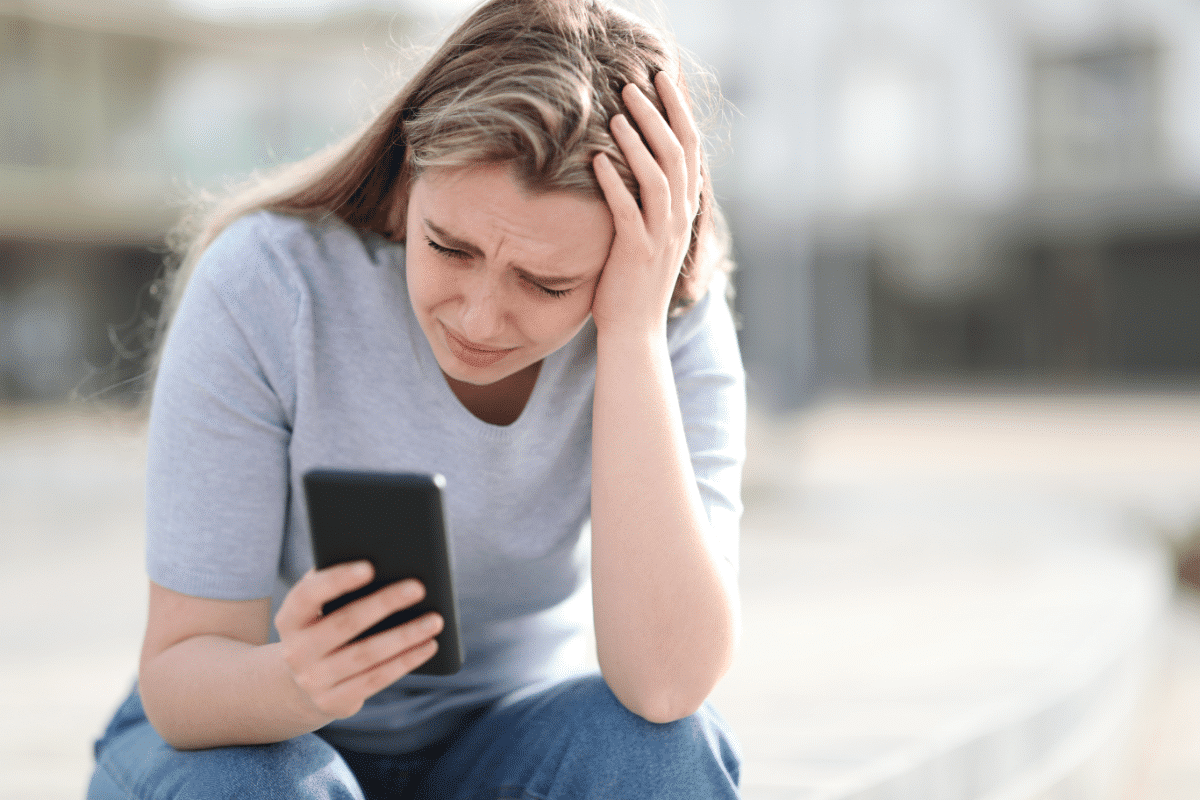 Sad teen checking bad news on mobile phone