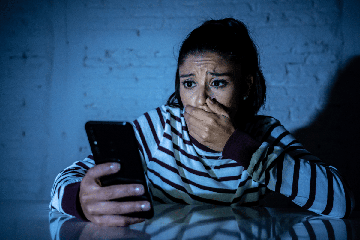 victim of cyberstalking viewing phone in shock