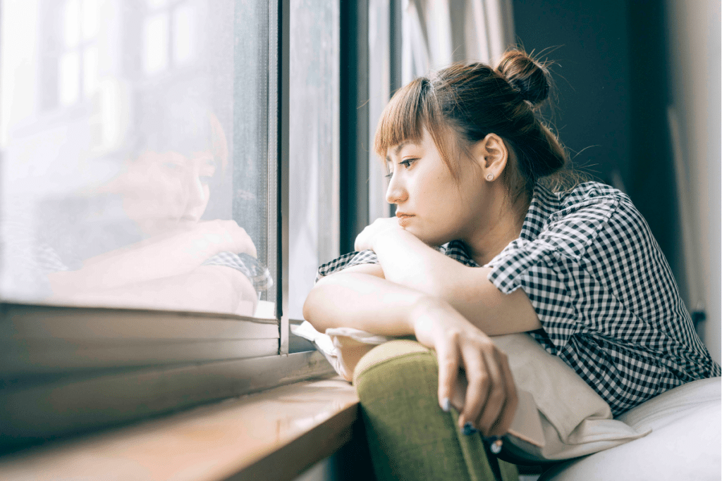 Teen girl feeling lonely looking out a window