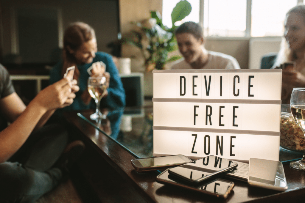 Group of friends playing cards with a "device free zone" sign in view