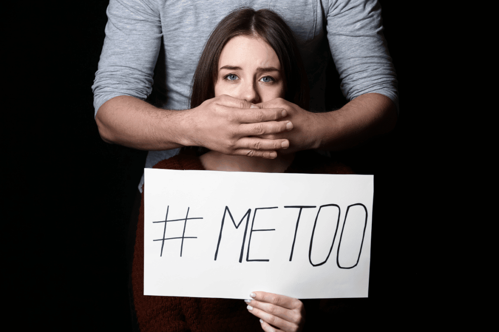 Girl holding a #MeToo sign with a man covering her mouth