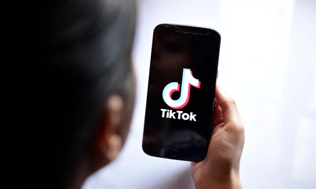 Person holding phone with TikTok app logo