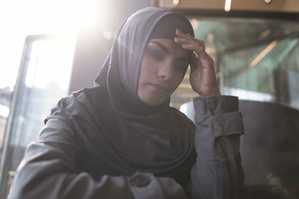 A woman with the hijab holding her head in a depressed state