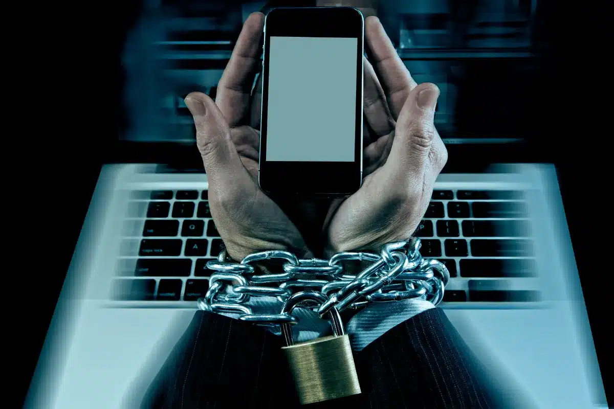hands holding a phone with chains around the wrists