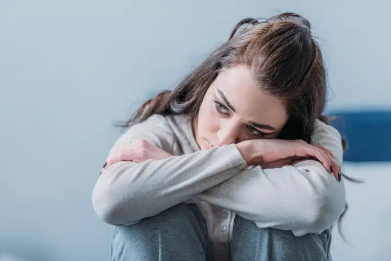 a girl with head in lap feeling anxious