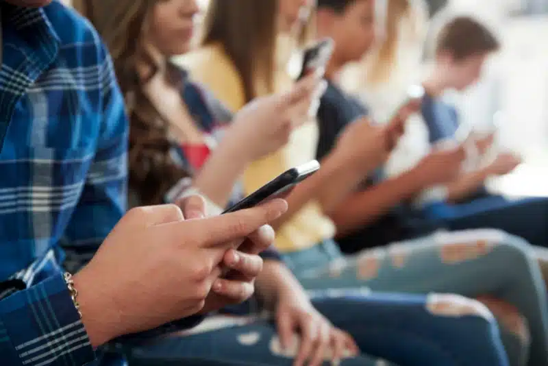 a group of teens sitting and scrolling on social media